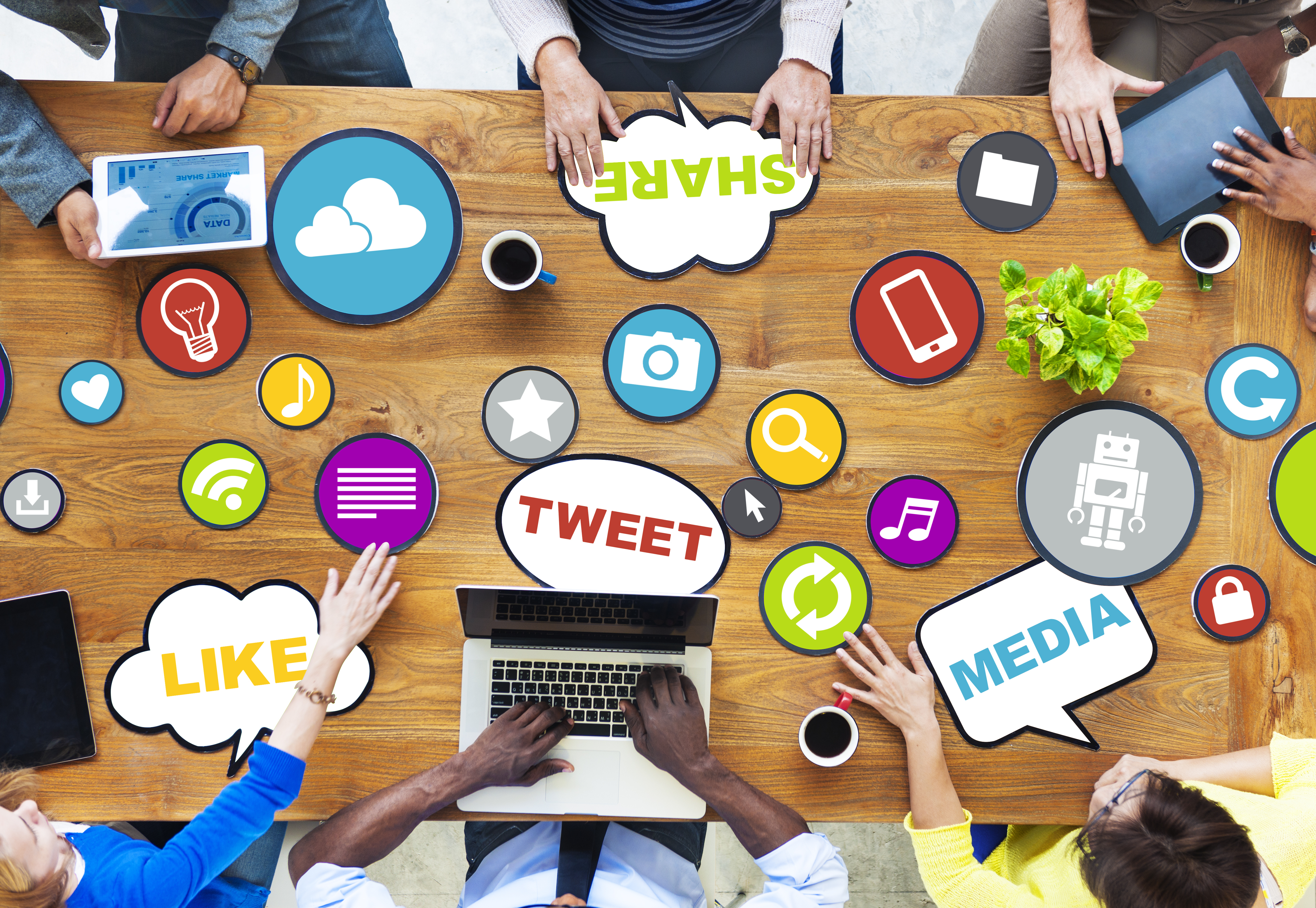 Image of people sitting around a table filled with social media icons
